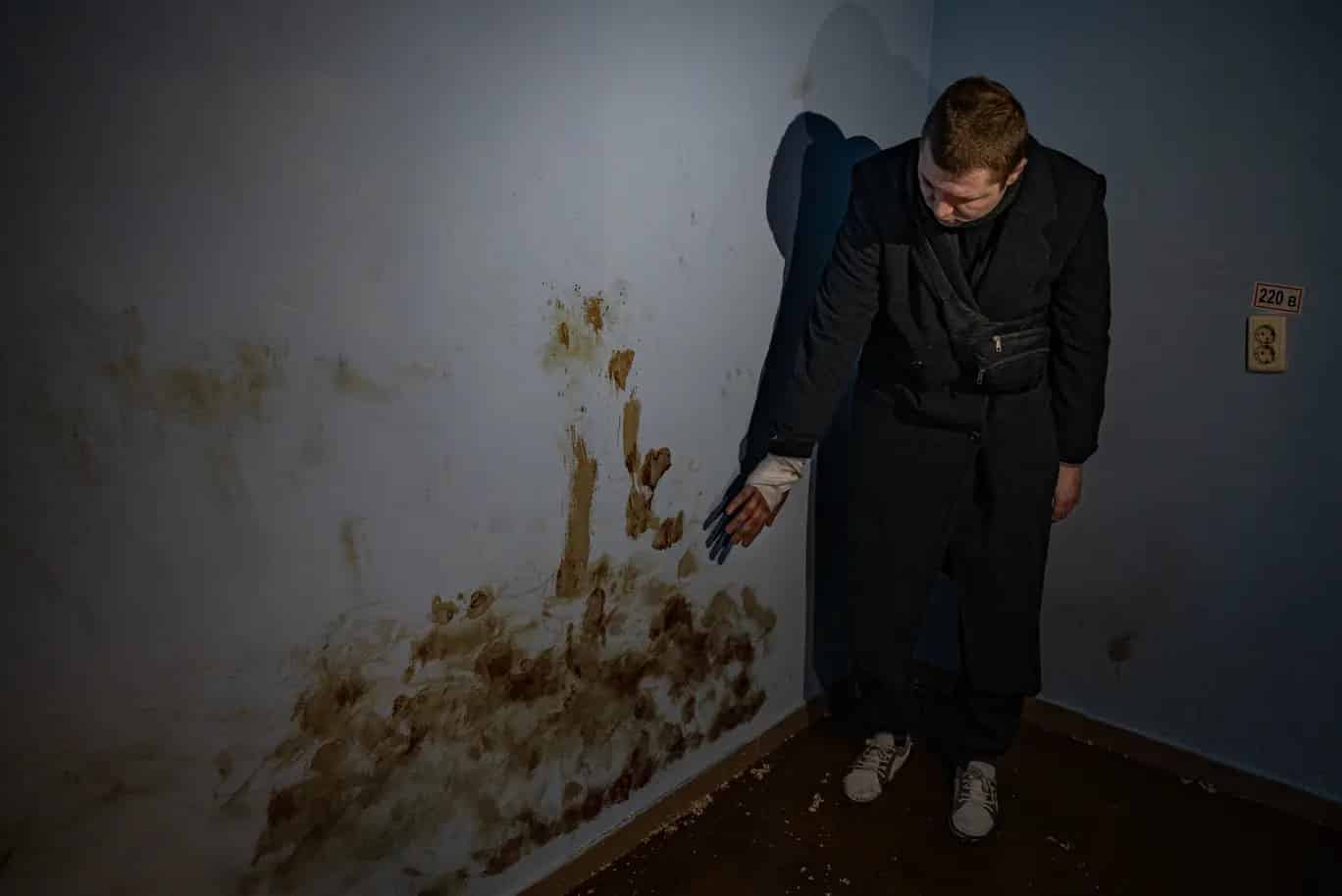 Andrej, egyike annak a nyolc civilnek, akit egy föld alatti kínzókamrában tartanak fogva Trostyanecben, vérét mutatja a cella falán / Fotó: Bel Trew